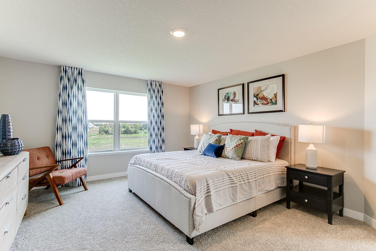 The large primary suite is separated from the other bedrooms by the loft area. Photo of model home, colors and finishes are similar.