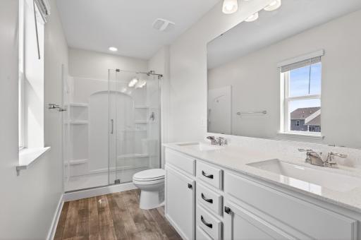 Primary bathroom with dual vanities and a large walk-in shower.