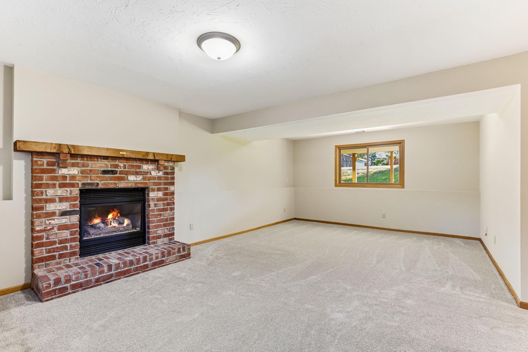 Beautiful family room highlighted by a classic brick gas fireplace, offering both style and comfort in a spacious, versatile setting.