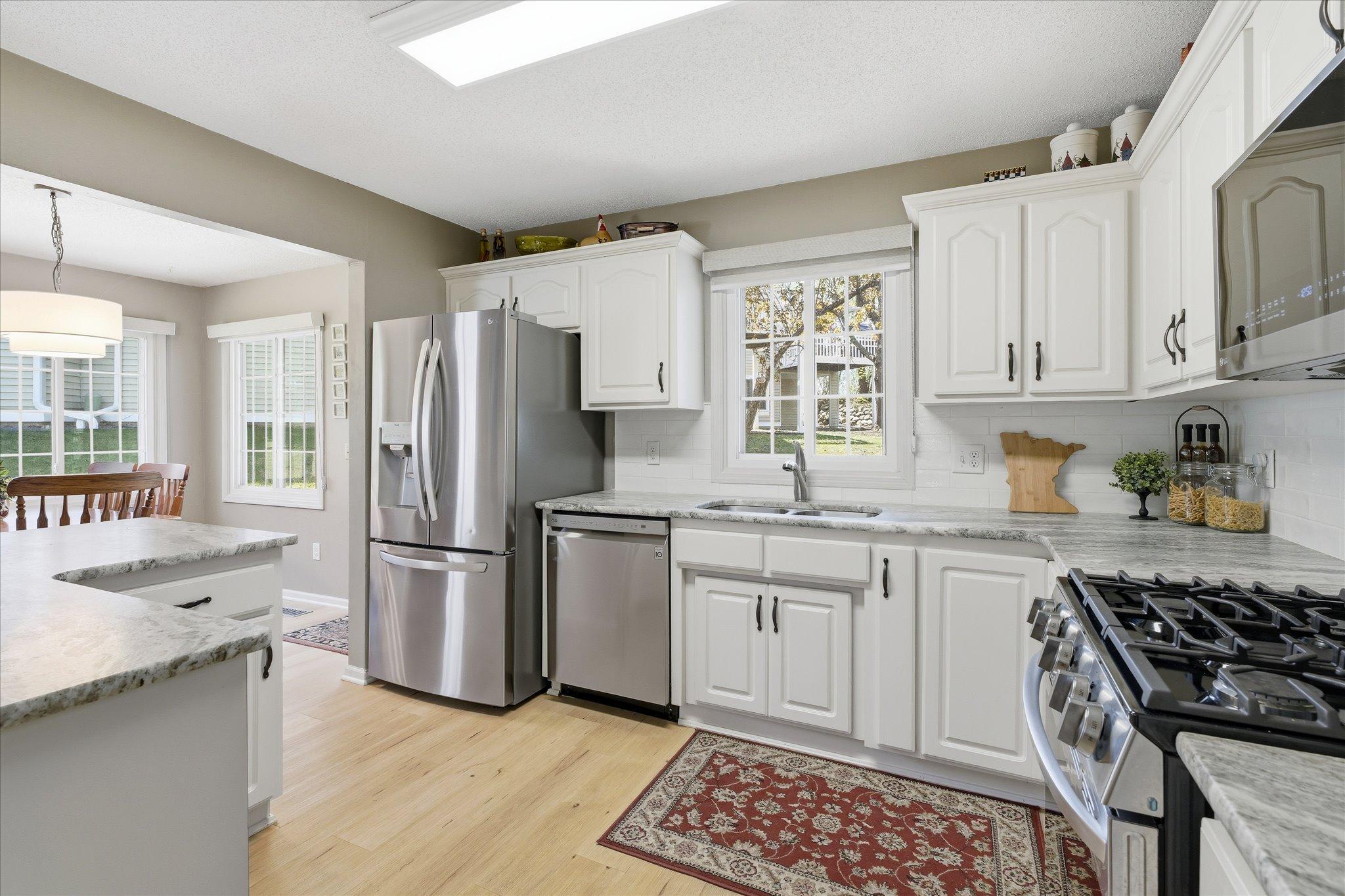 Bright and updated kitchen featuring white cabinetry, granite countertops, stainless steel appliances, and abundant natural light.