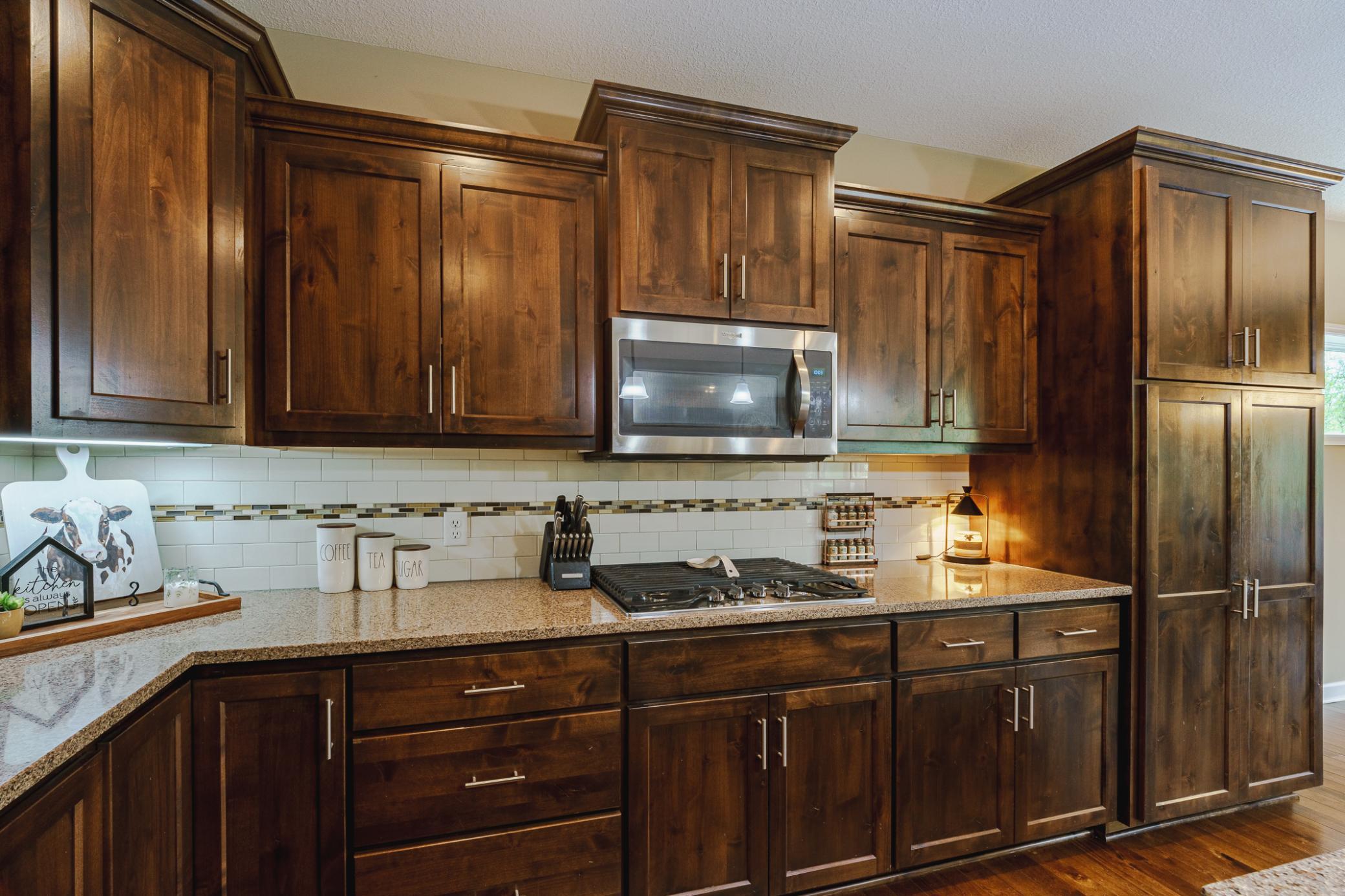 The kitchen includes quartz countertops and staggered 36” knotty alder cabinetry with roll-out shelves.