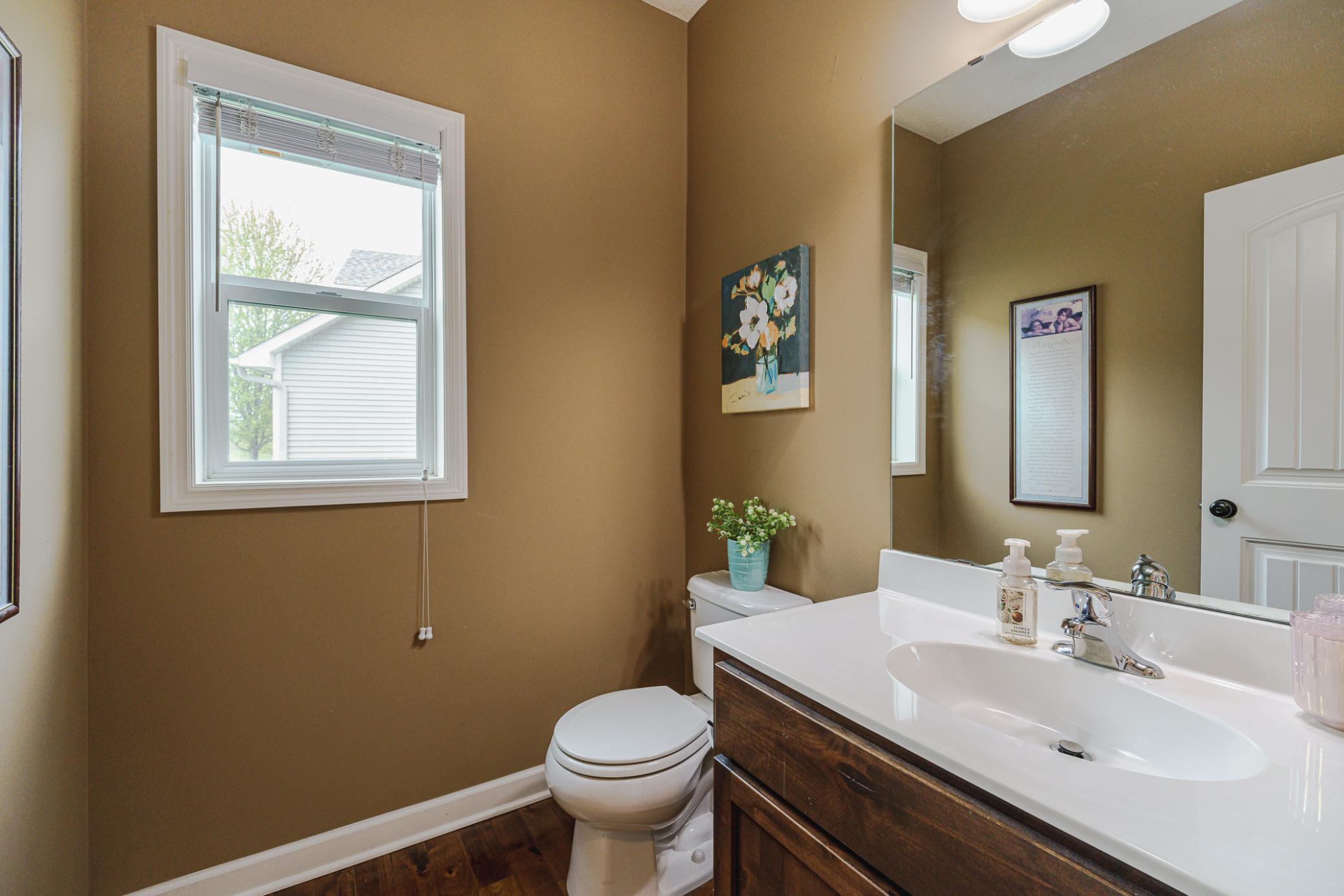 A half bath with hardwood flooring lies near the bedroom/office.