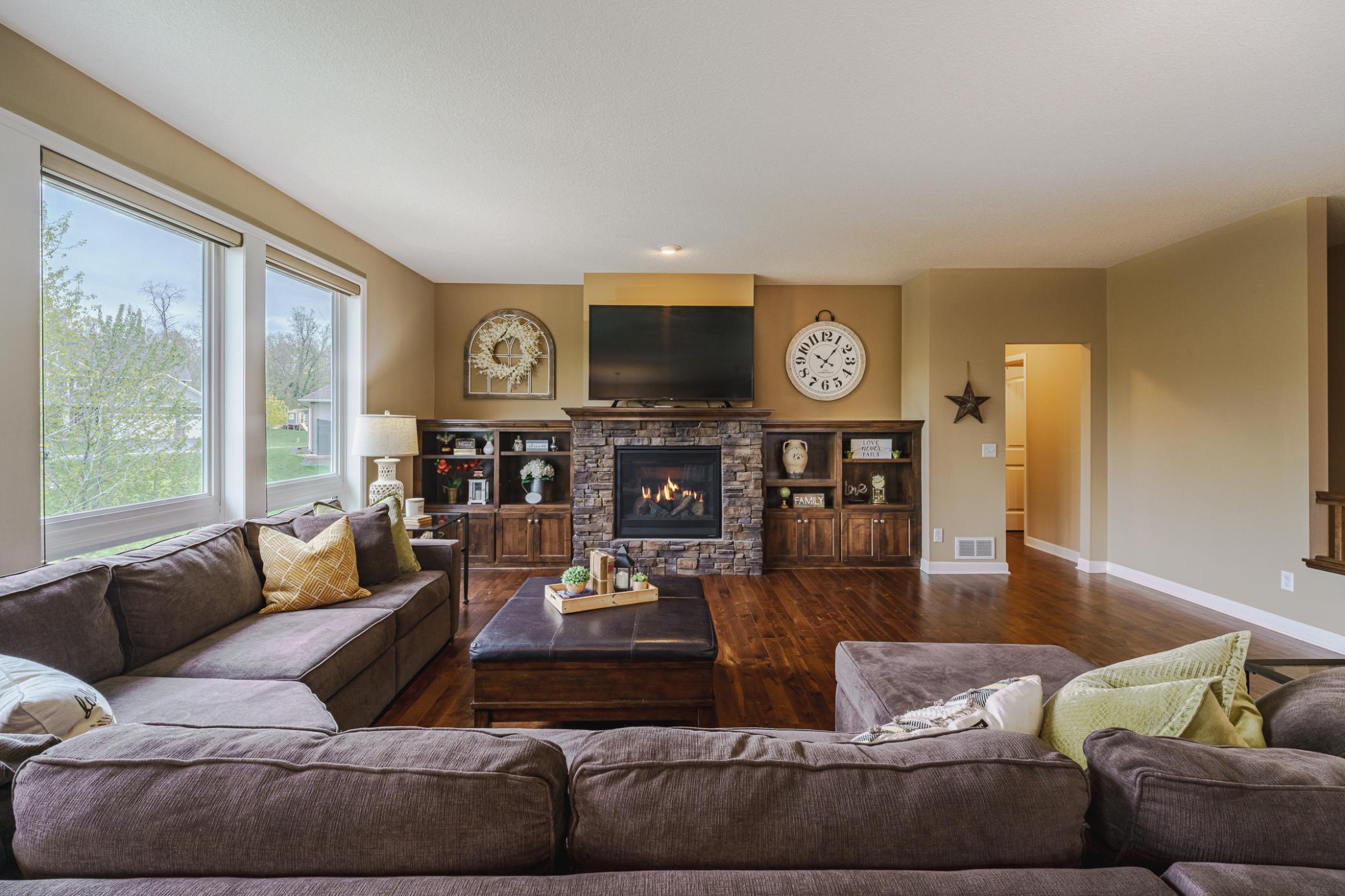 The main floor living room has a stone fireplace anchored by a wood mantle and knotty alder built-ins on either side of the fireplace, and three large windows. This room has a tech tube.