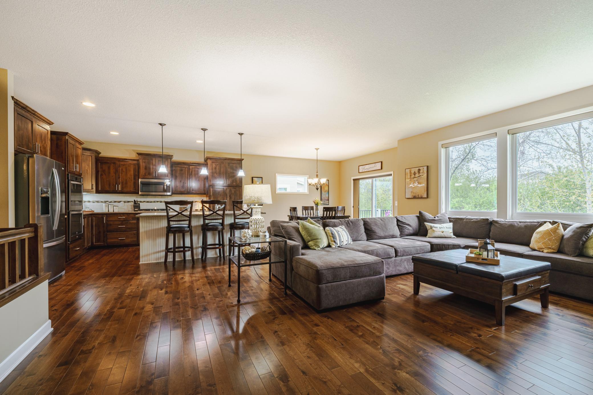 The living room opens to the kitchen. This room receives wonderful natural light and views of green foliage behind the home.