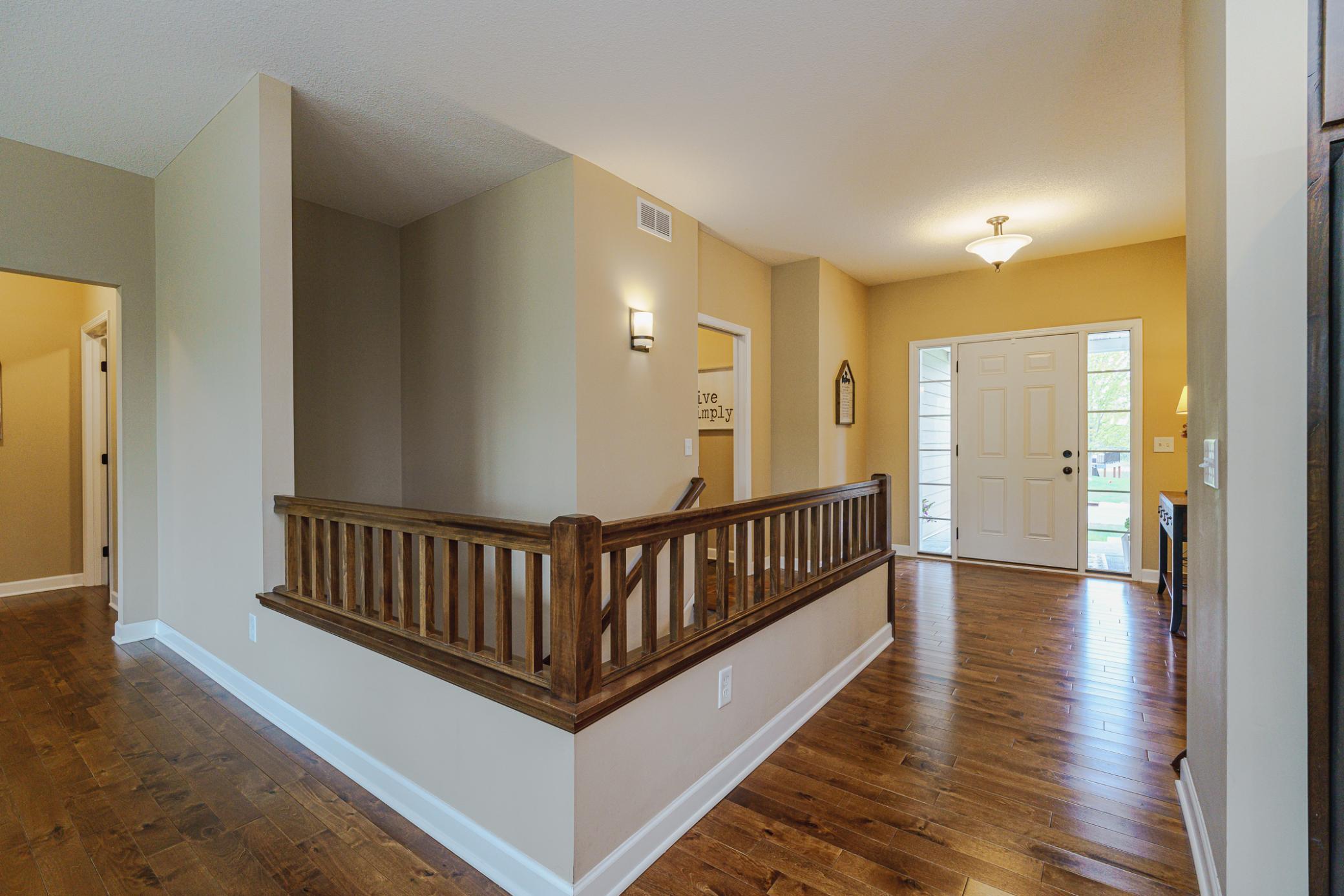 The main entry hall leading to the lower level is wide and bright. The balusters have clean lines.
