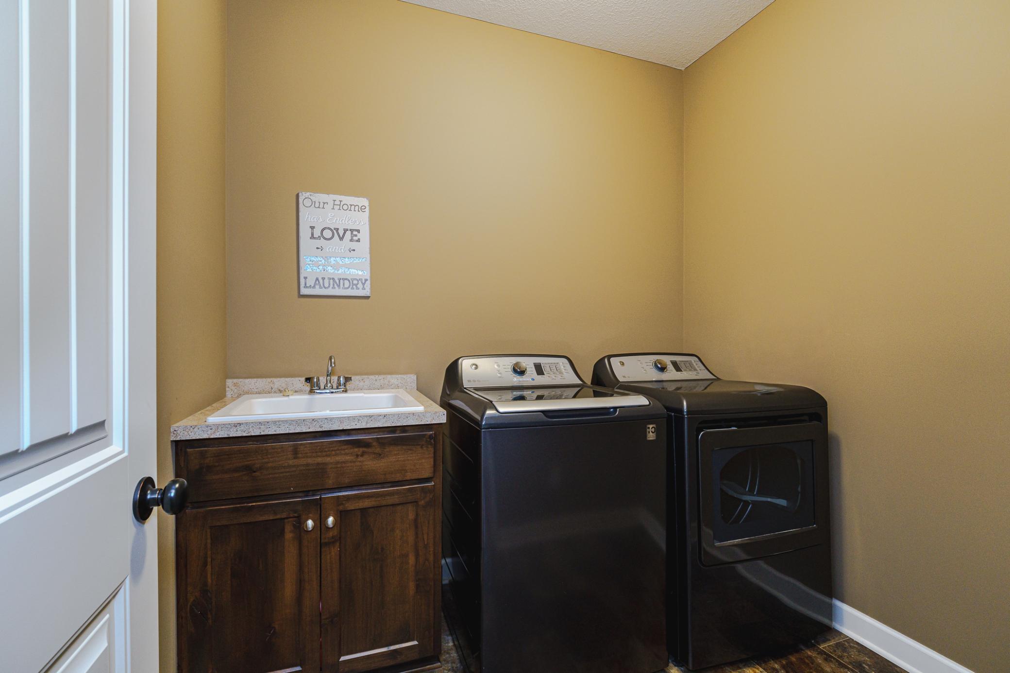 The laundry room lies off the primary suite and has durable vinyl flooring and a handy utility sink.