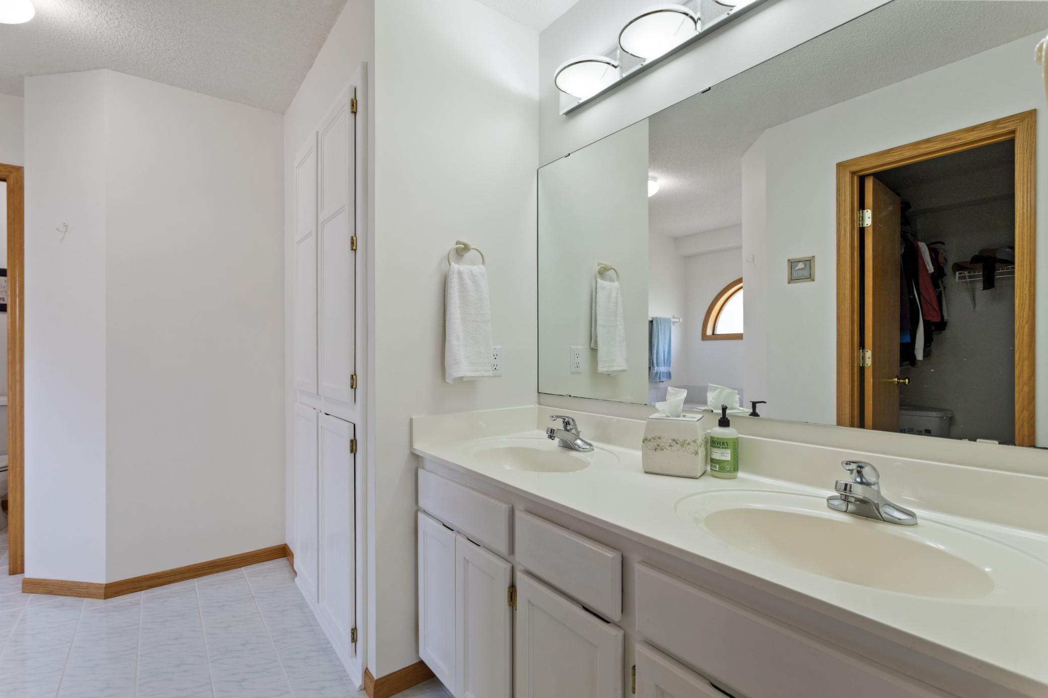 Owners Suite Bath with 2 wide linen closet, Vanity with 2 sinks, and tiled flooring