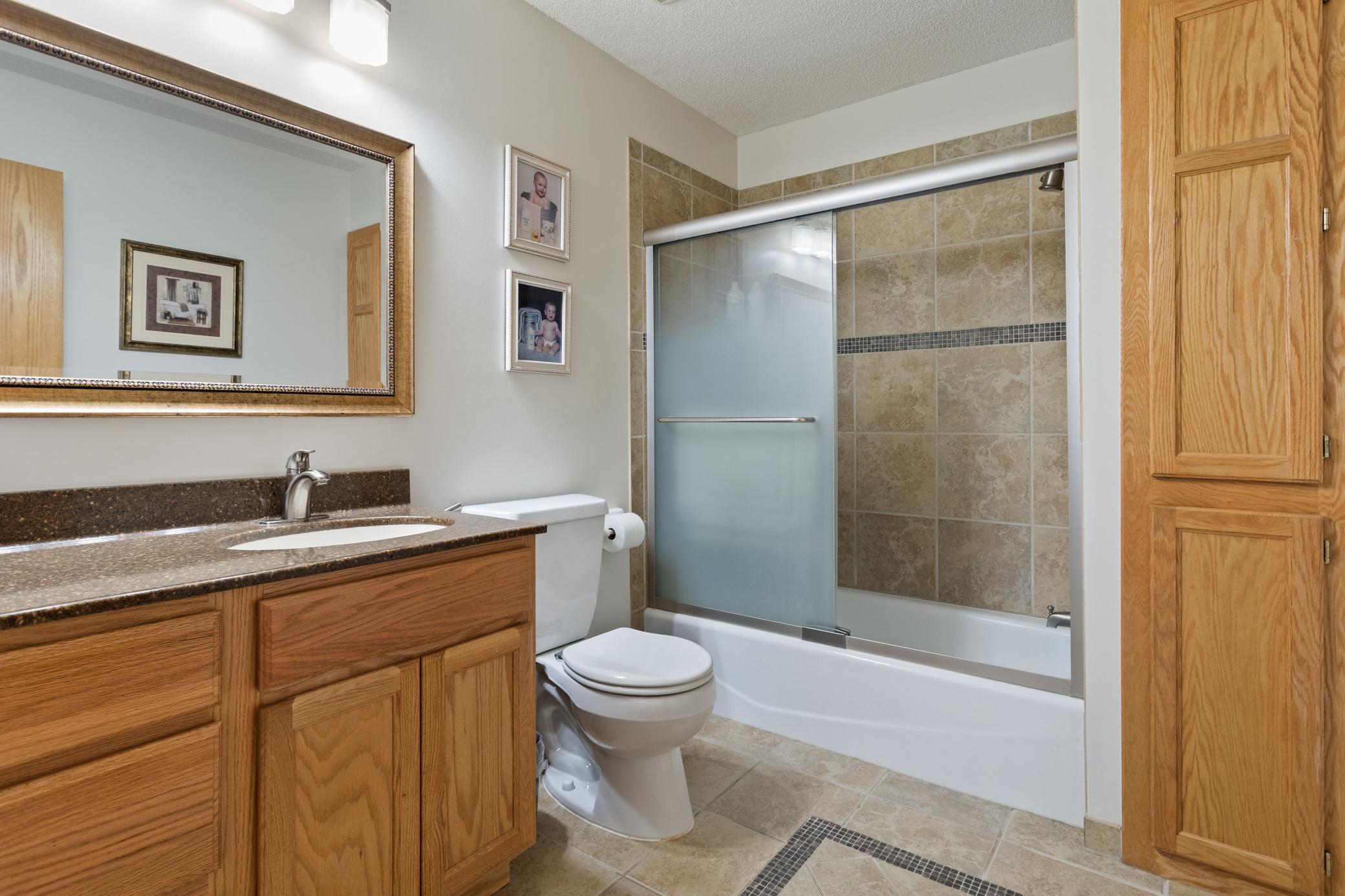 Main level bath between two bedrooms. Tiled floor, upgraded vanity top, and tiled shower with shower doors installed