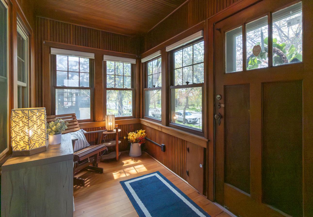 Enter through a cozy sunroom/front porch, highlighted by timeless woodwork details and beautiful hardwood floors