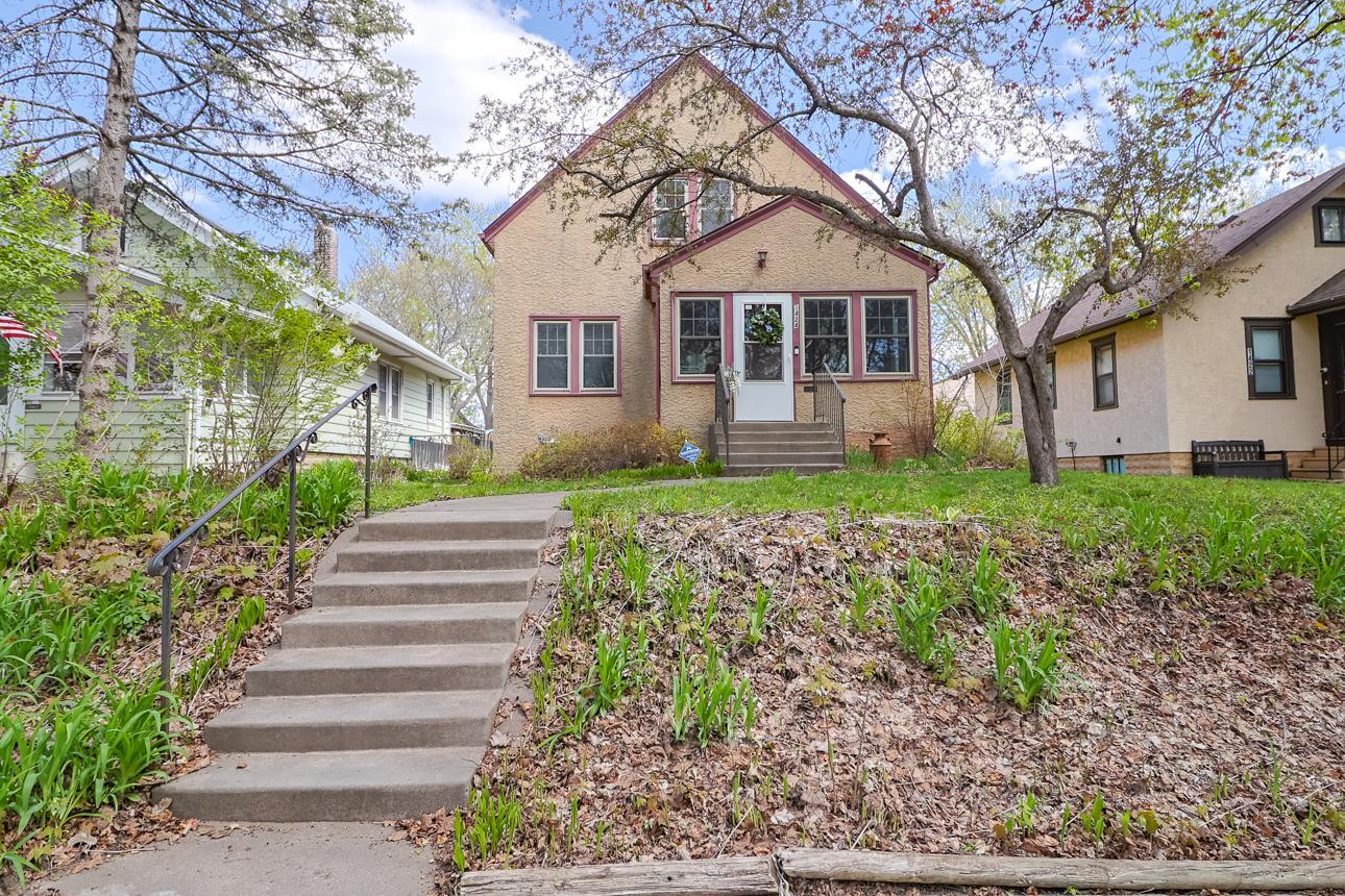 Wonderful curb appeal featuring a welcoming walkway and stairs leading from the sidewalk past flowering trees and garden space