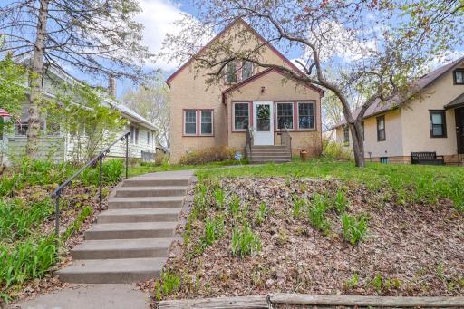 Wonderful curb appeal featuring a welcoming walkway and stairs leading from the sidewalk past flowering trees and garden space