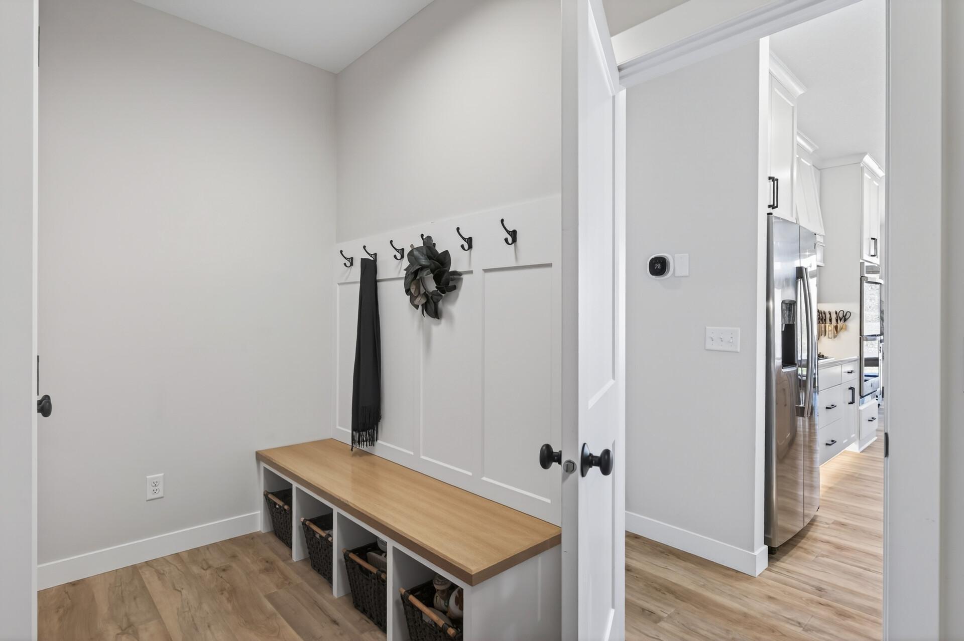 Convenience meets function with a well-designed laundry and mudroom just off the garage, complete with a sink and built-in bench, along with an additional built-in drop zone near the front entry