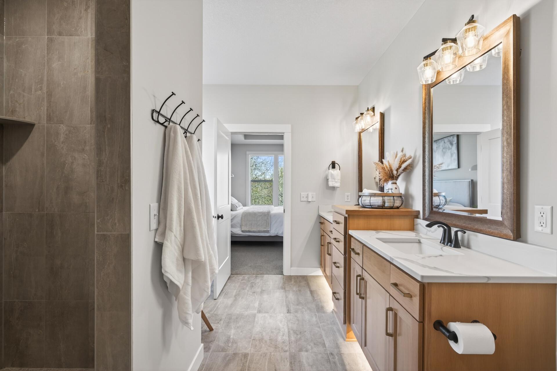 uxurious ensuite with dual vanities, quartz countertops, a walk-in shower, soaker tub, and walk-in closet