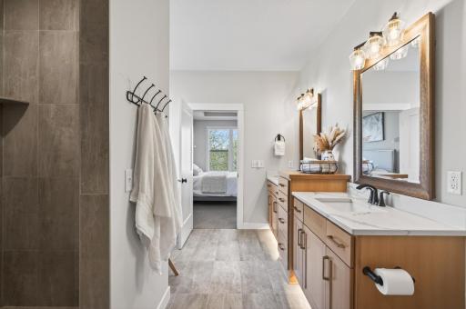 Luxurious ensuite with dual vanities, quartz countertops, a walk-in shower, soaker tub, and walk-in closet