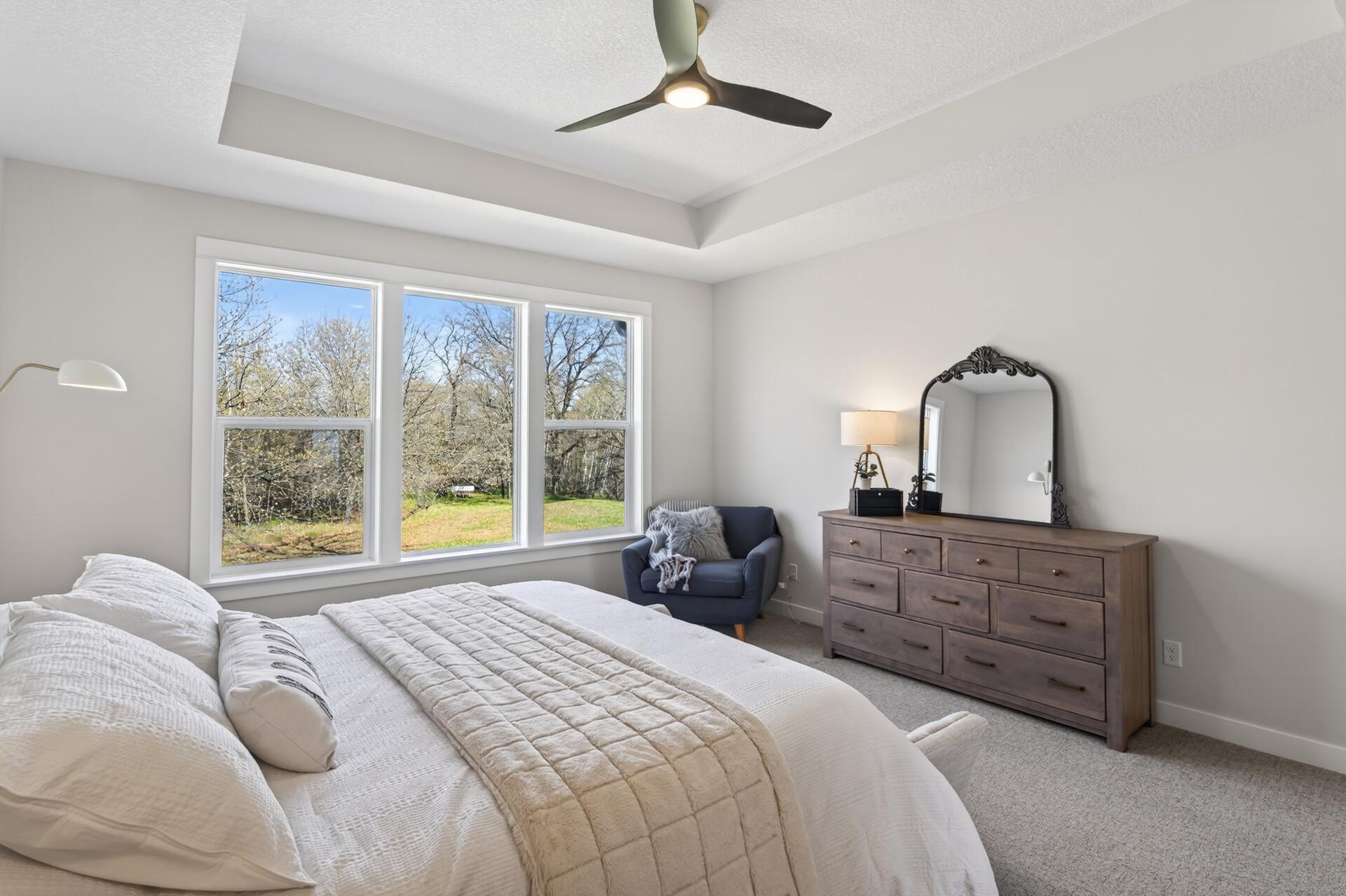 The spacious primary suite is privately situated on one side of the home and features a tray ceiling, beautiful backyard views