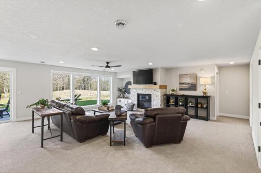 The finished walkout lower level expands the living space with a large family room, wet bar, and a second gas fireplace with brick surround, built-ins, and a white oak mantle, creating a warm and inviting atmosphere.