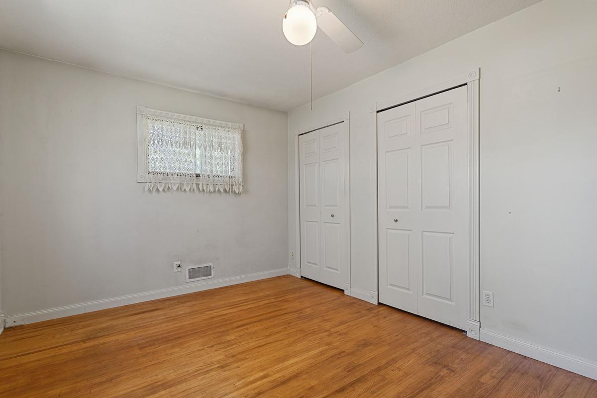 Upper-level bedroom featuring warm hardwood floors and a ceiling fan. This room offers excellent storage with two separate closets.