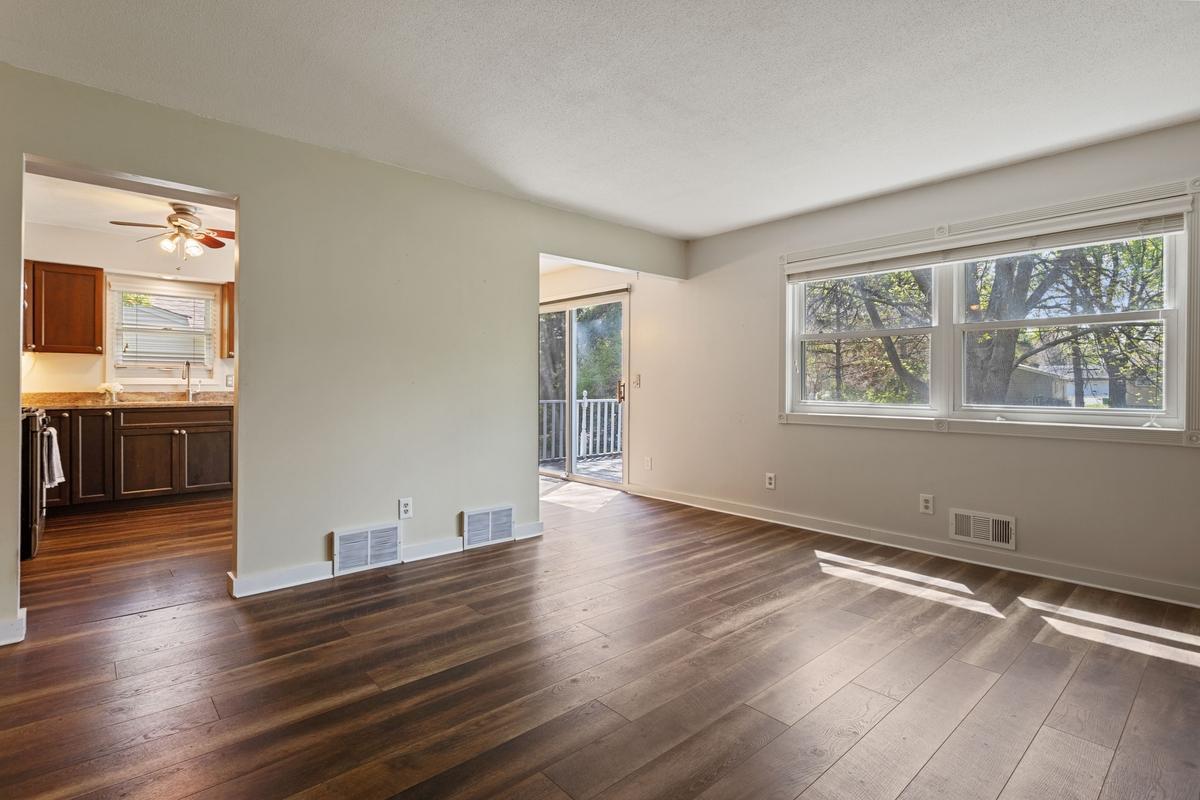 Light and bright living room with south-facing windows and abundant natural light. Enjoy peaceful views of a fenced backyard with mature trees, offering privacy and a relaxing natural backdrop.