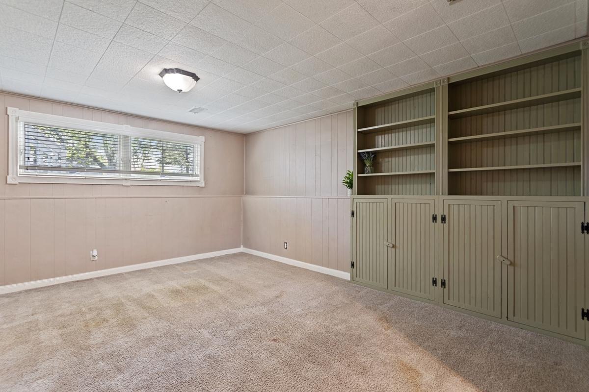 The lower-level family room has a built-in bookshelf that provides both open shelving and closed-door storage for added functionality. Lookout windows bring in natural light and offer views of the backyard.