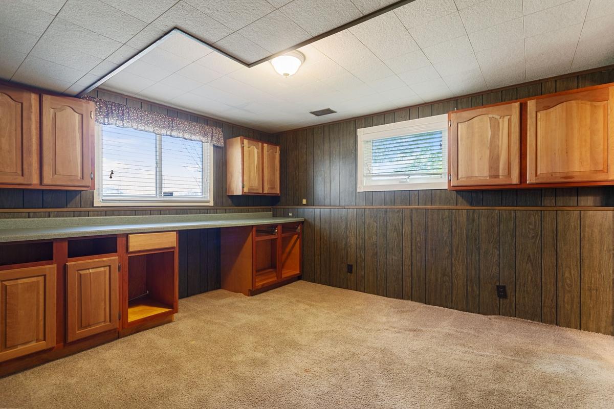 Lower-level bedroom filled with natural light. The room features wall cupboards and countertop workspace that was once used as a sewing area. While previously used as a hobby room, it is a true bedroom with private ensuite bathroom.