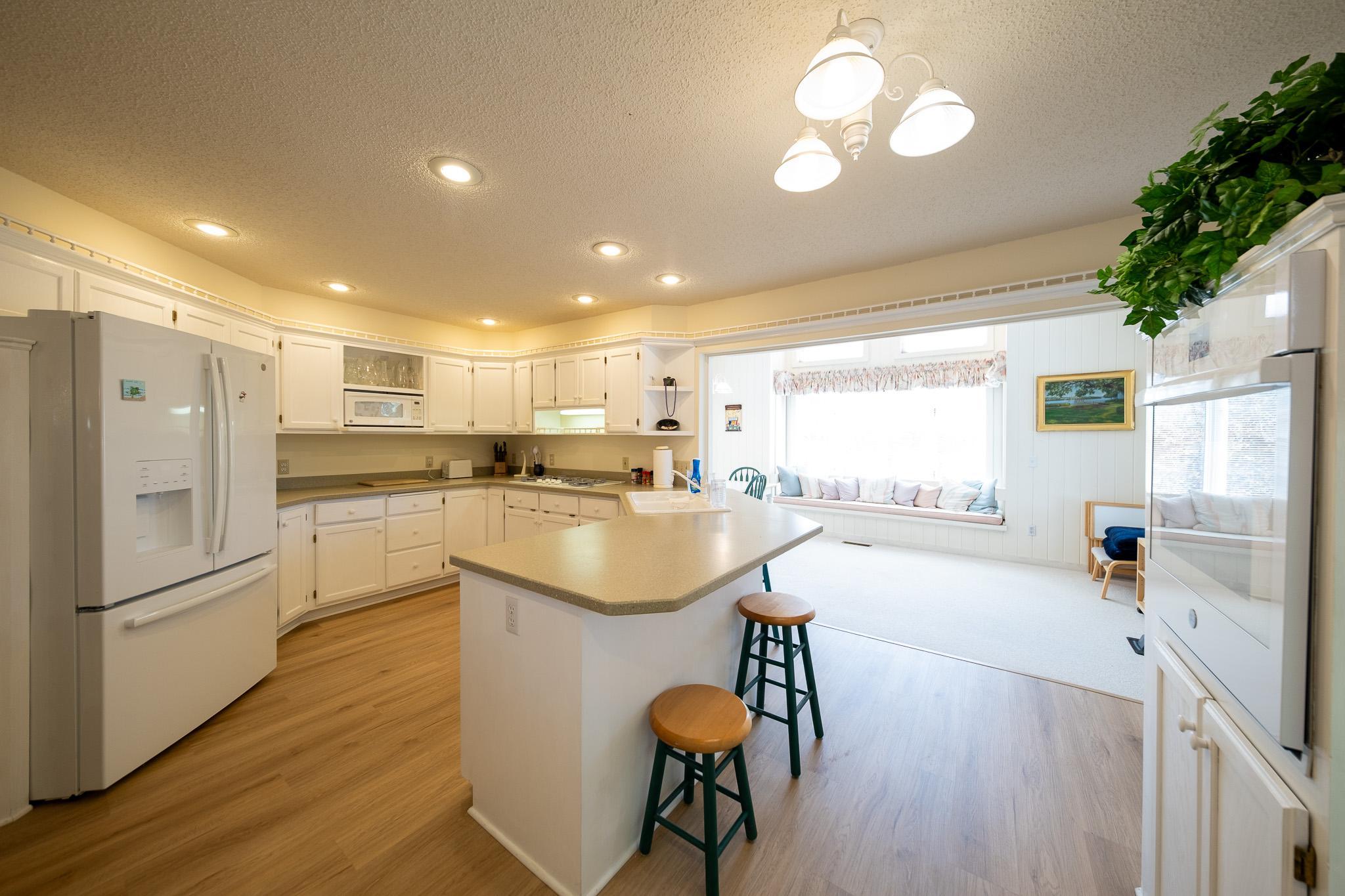 Kitchen with large wrap around bar counter and white appliances
