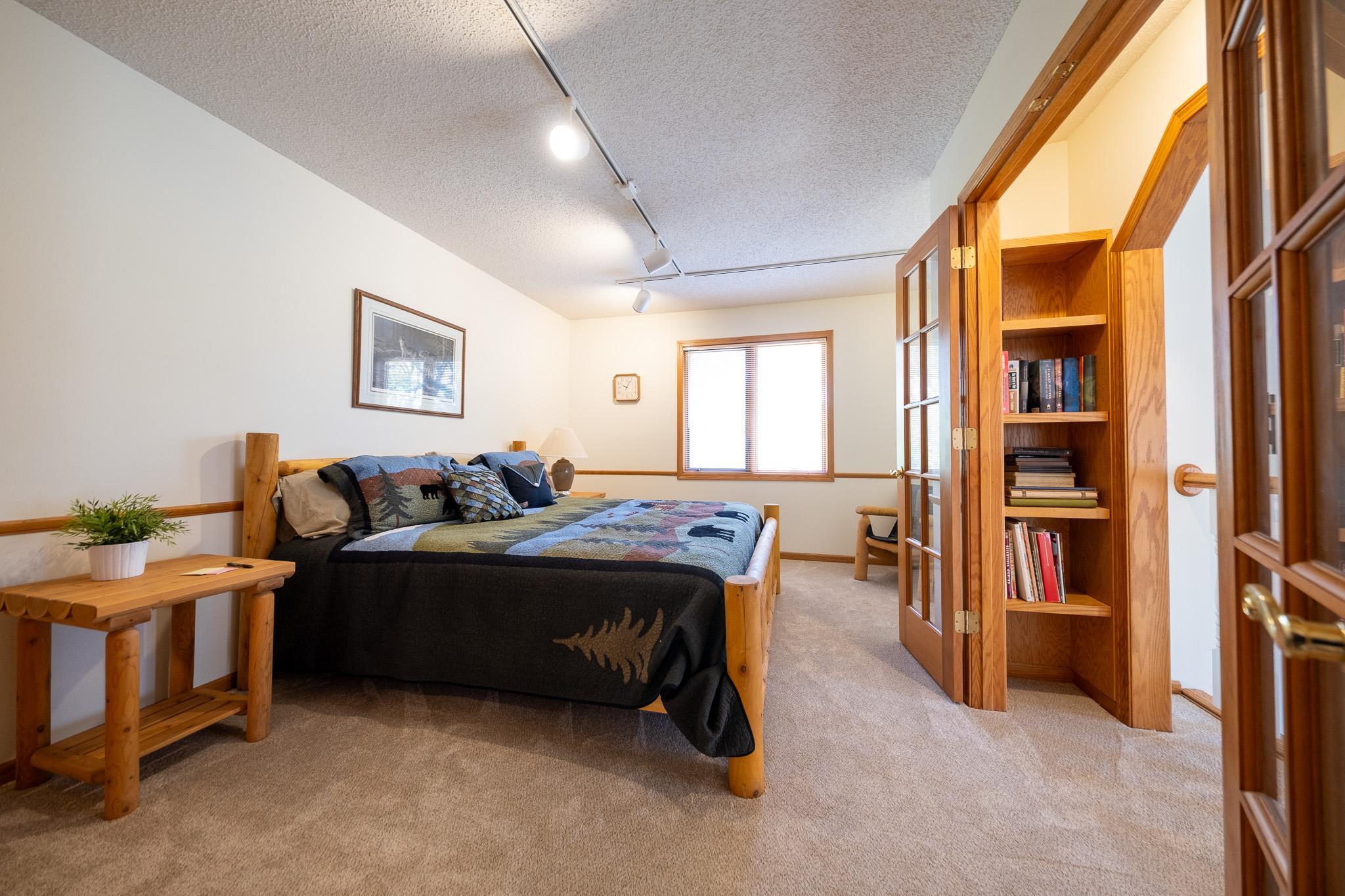 One of the two upper bedrooms, this one has French doors leading to bookshelf area and balcony overlooking the main area