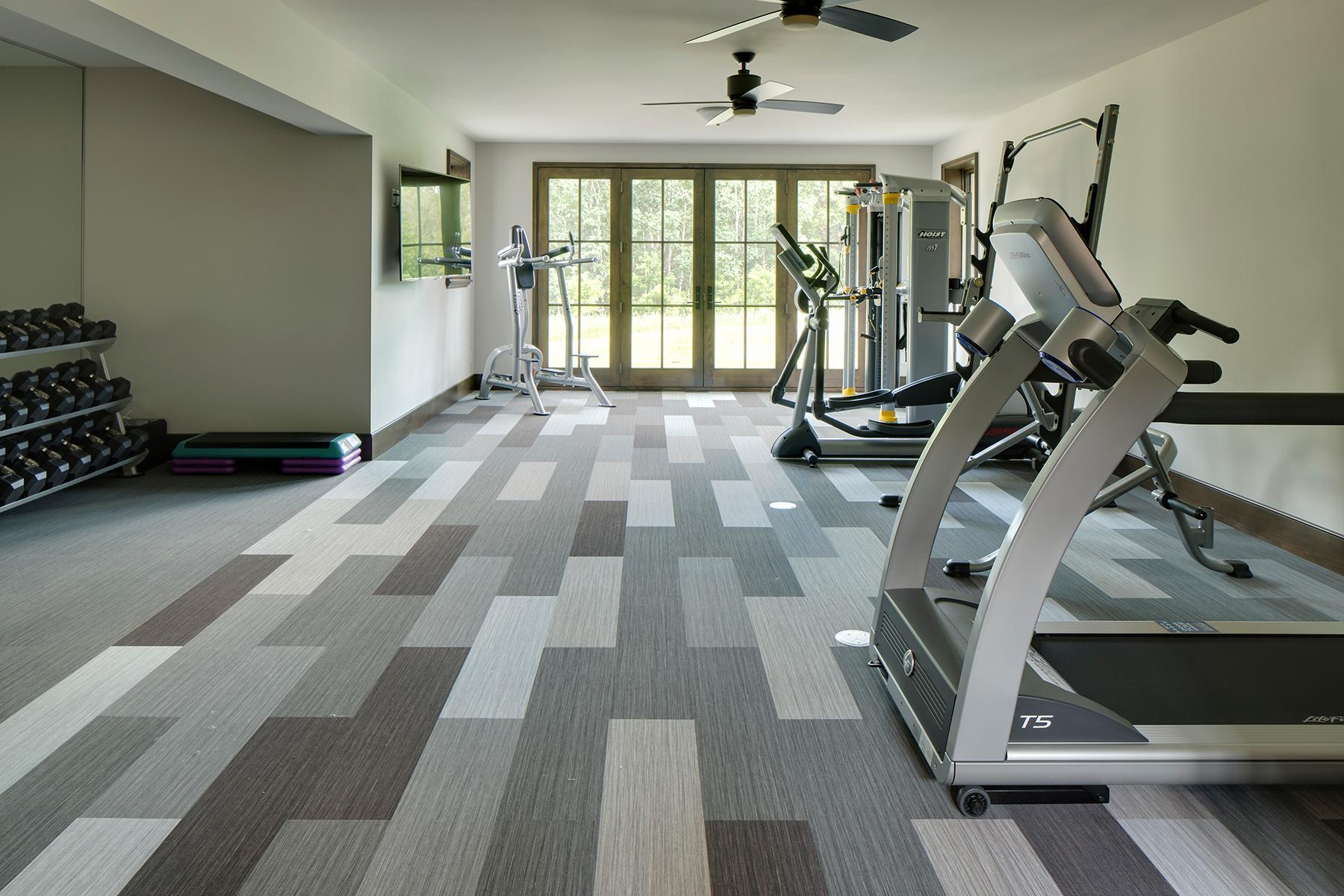 Expansive gym area with full mirror and French doors opening to backyard