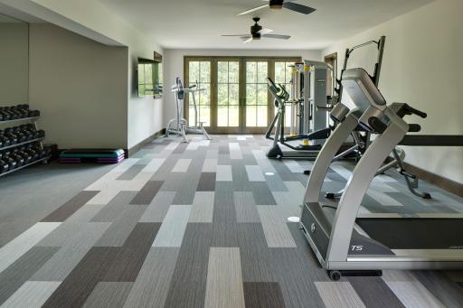 Expansive gym area with full mirror and French doors opening to backyard