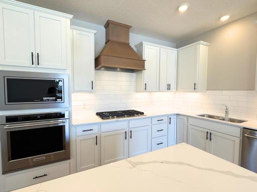Rightsizing or downsizing doesn't mean you have to give up a great kitchen! Your gourmet kitchen includes a 5-burner gas cooktop, wood vent hood, a built-in microwave and oven, and beautiful quartz counters.