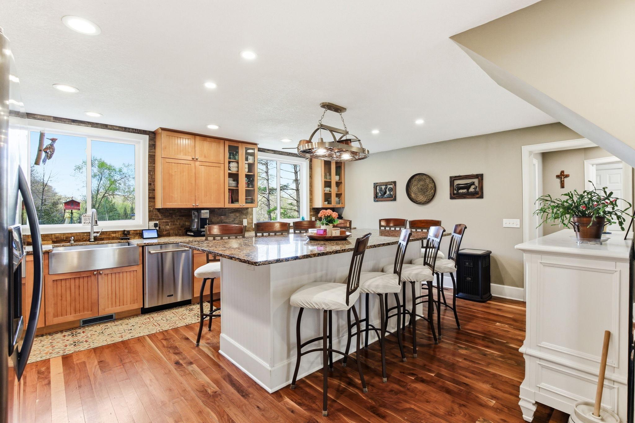 Large eat-in Kitchen with granite counters, massive island seating, and warm wood floors - built for gathering.