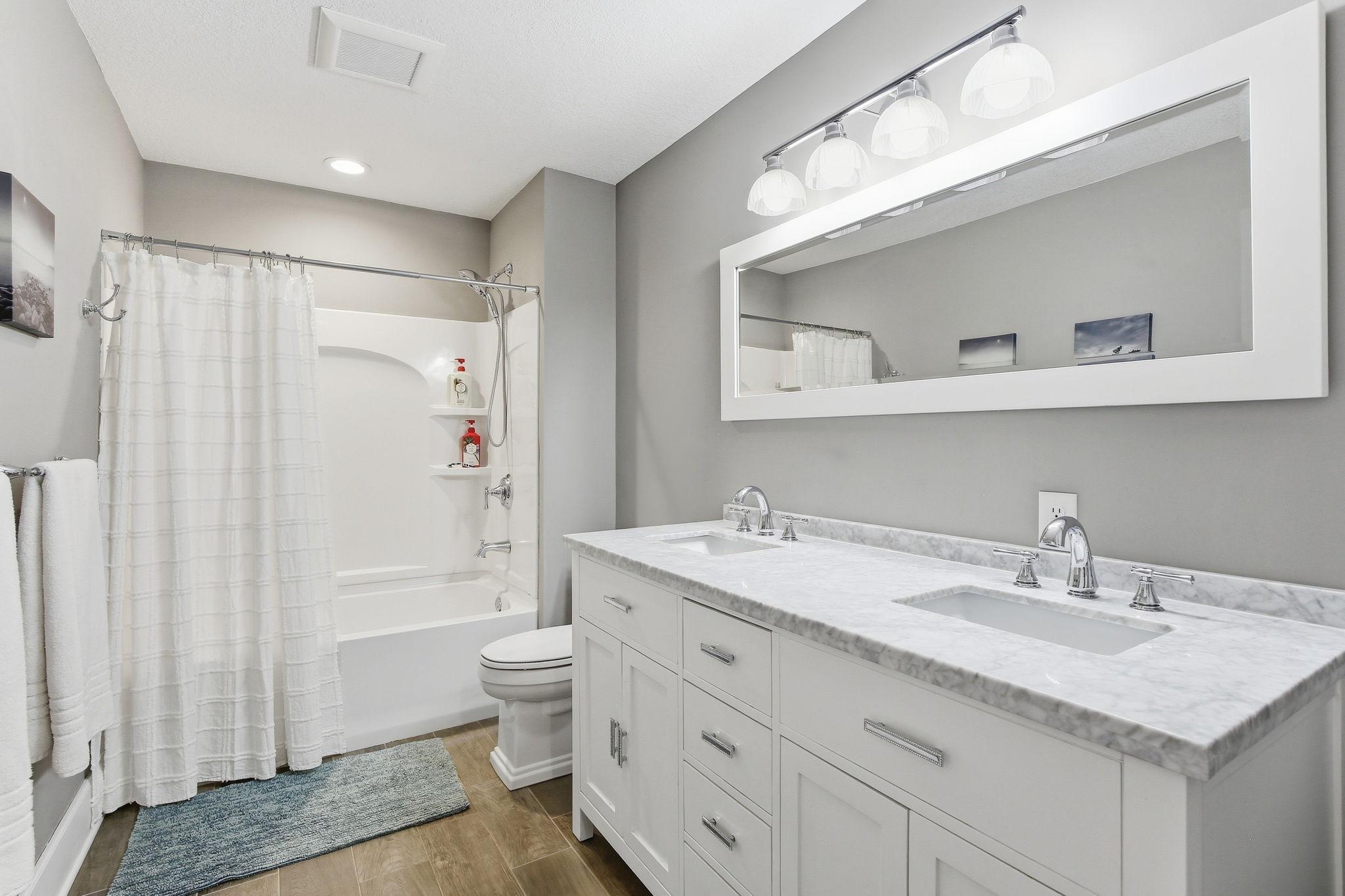 Updated full bath with double vanity, solid surface countertops, and clean finishes.