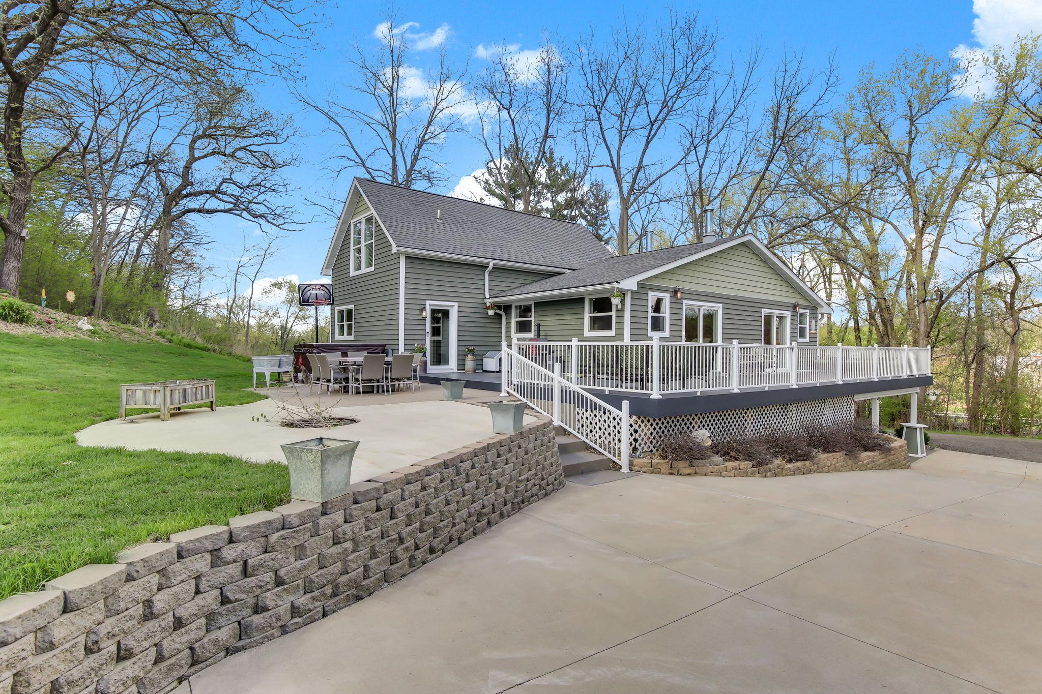 Expansive Patio and Deck setup - perfect for entertaining with multiple seating areas and a private, tree-lined backdrop.