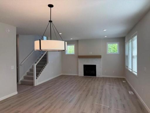 Main floor Gathering Room with elegant tiled gas fireplace, plus blinds included!