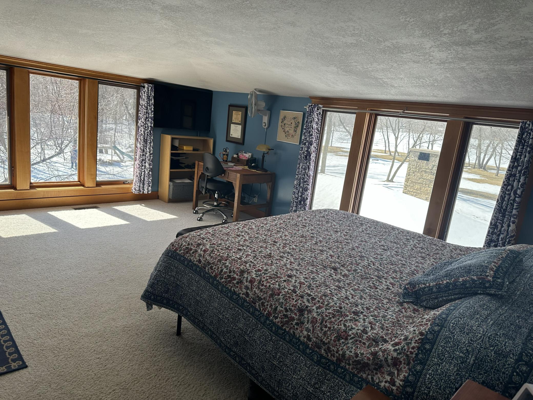 Upper level Primary bedroom with lots of natural lighting overlooking the backside of home.