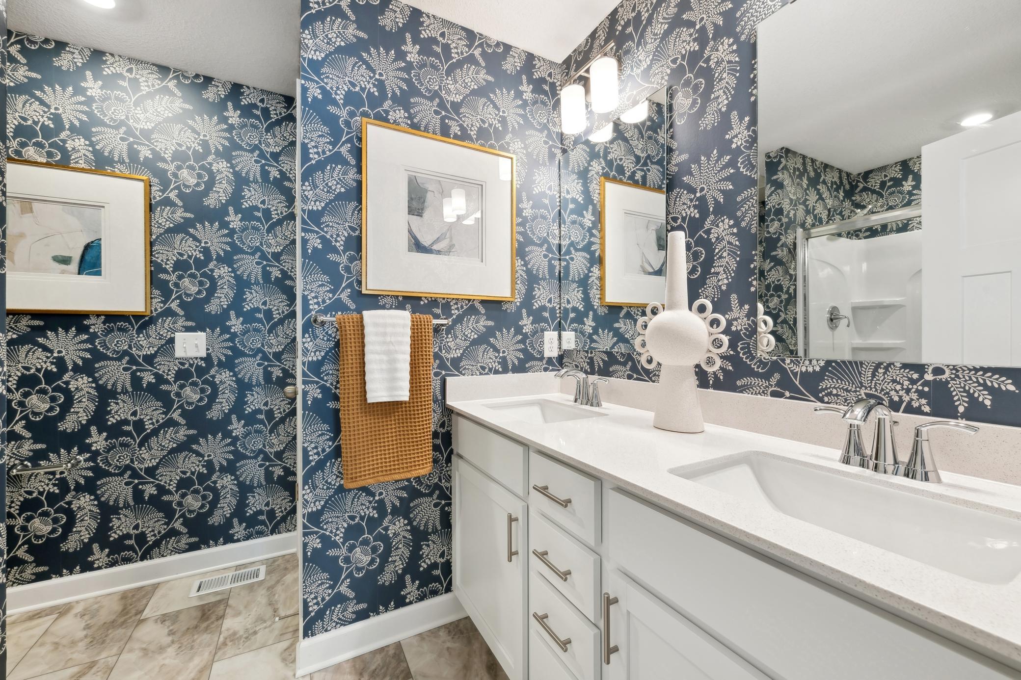 (Photo of decorated model, actual home's finishes will vary) The owner's bathroom offers a double-vanity with quartz countertops, a linen closet, and shower.