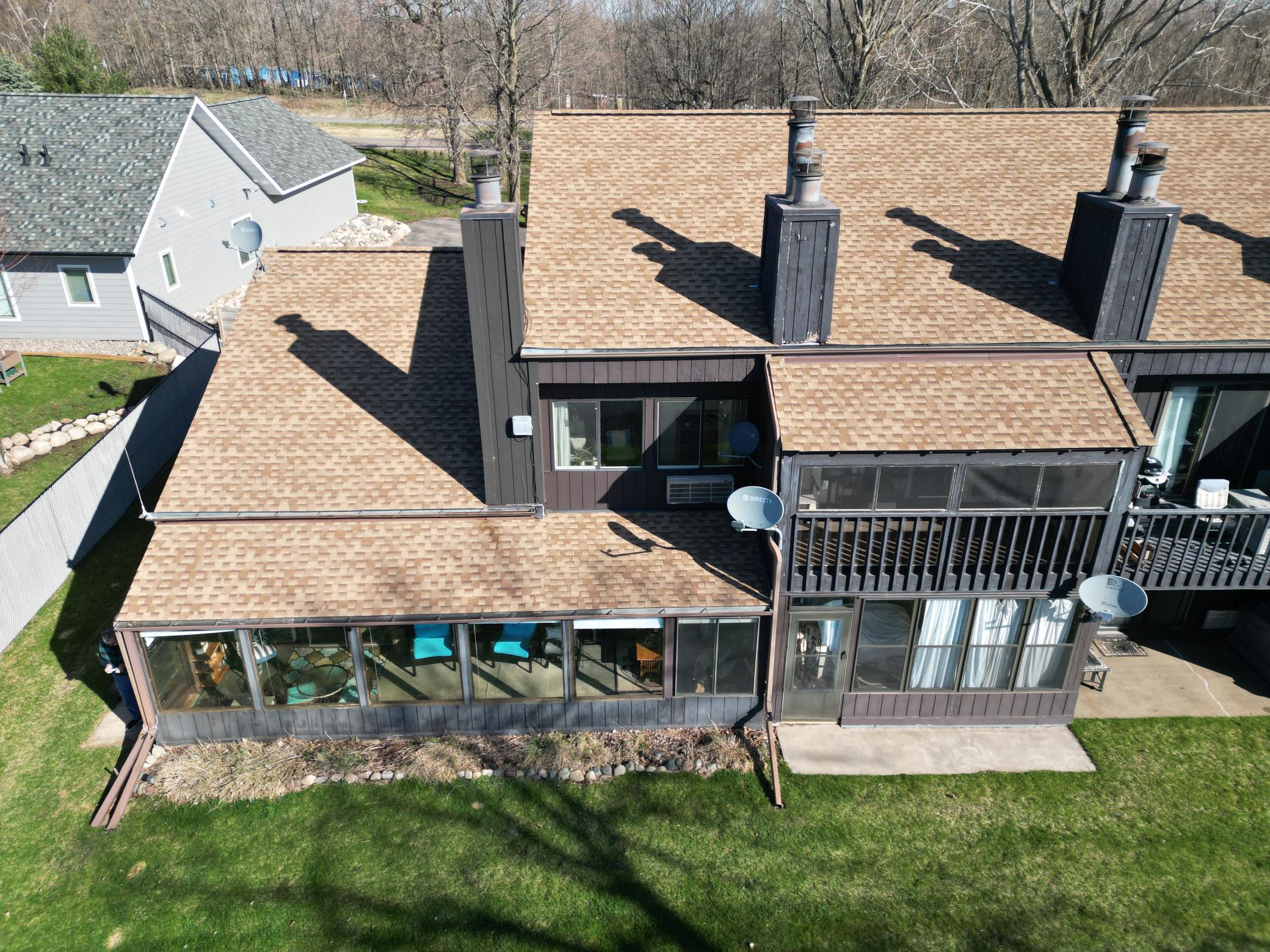 View of condo #138 & 139 on the left end of the building. Shows the lake side porch with the bright chairs. Roof was replaced in 2024.
