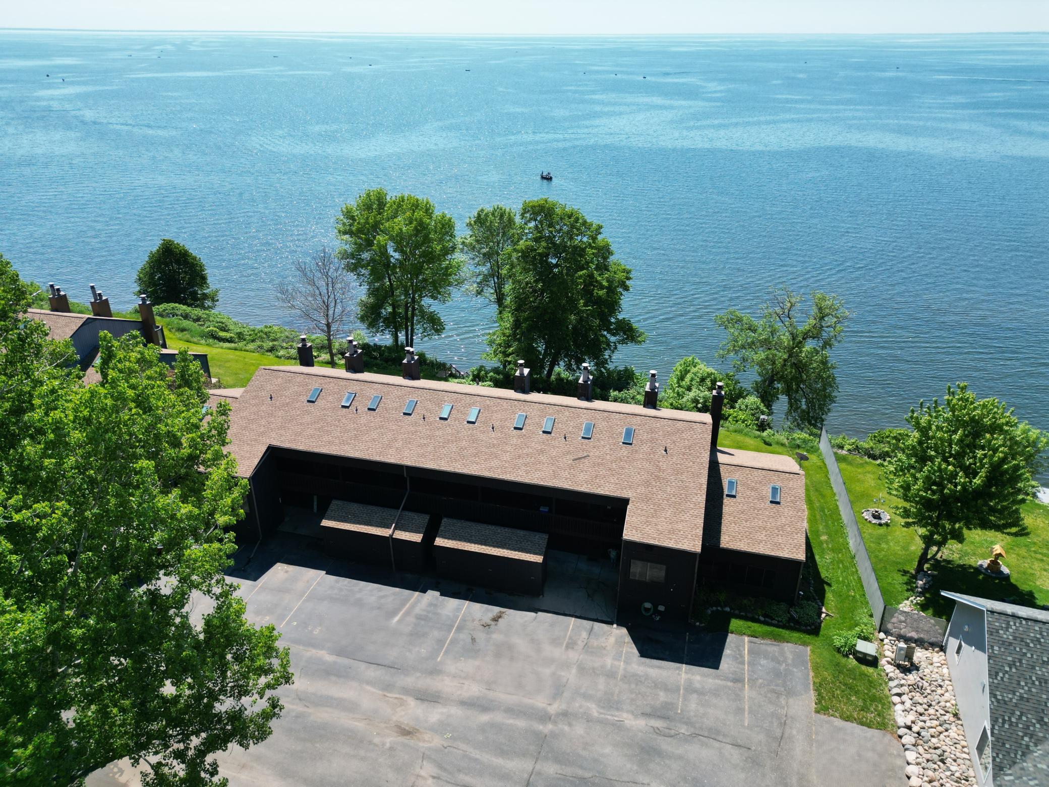 Aerial view of the building right off the waters edge. The roof is only a couple years old and the skylights were new when the roof was replaced in 2024. This condo provides two private parking spaces.