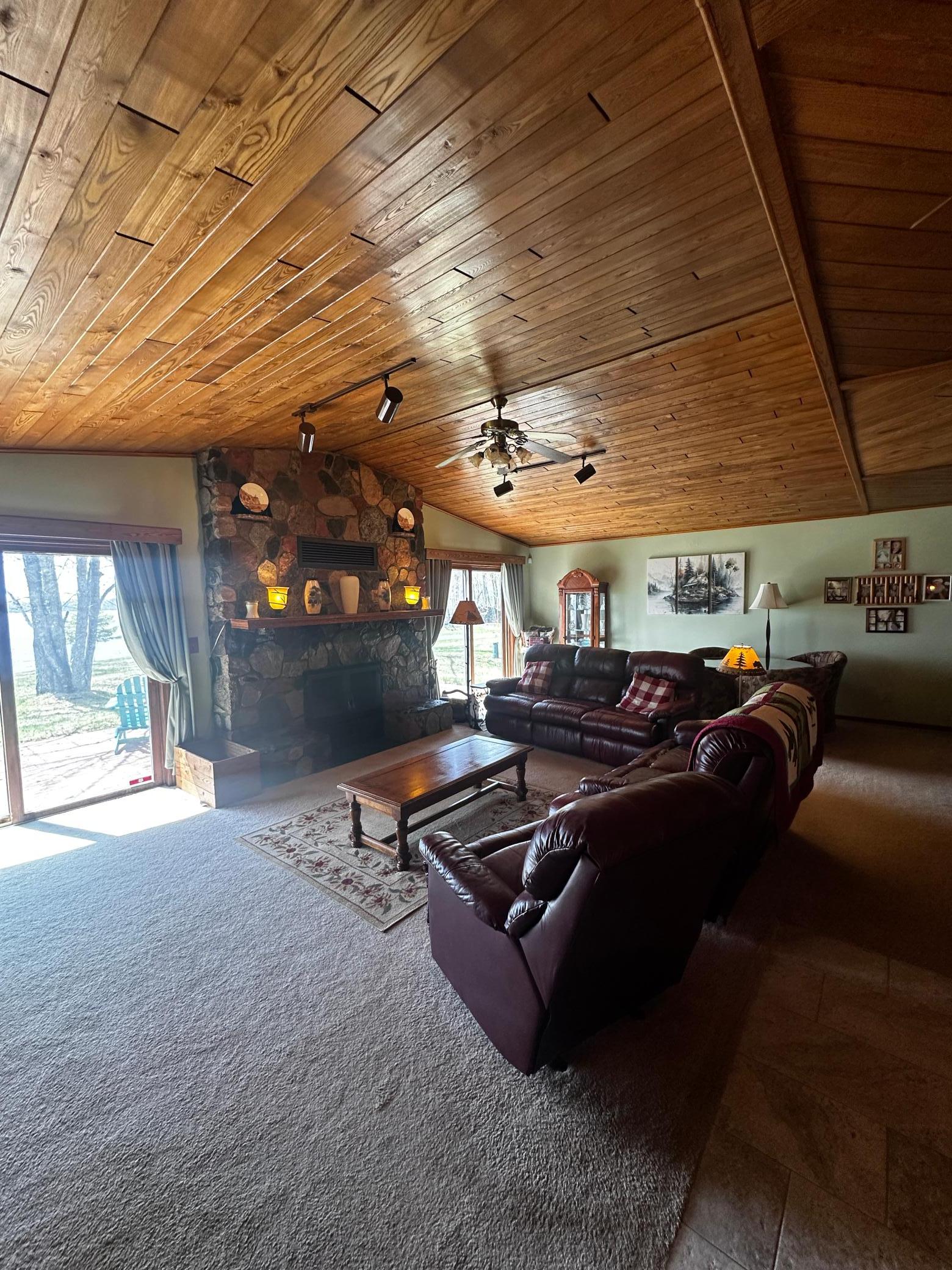 Living room with split granite stone fireplace, black ash ceiling, water views and access to patio