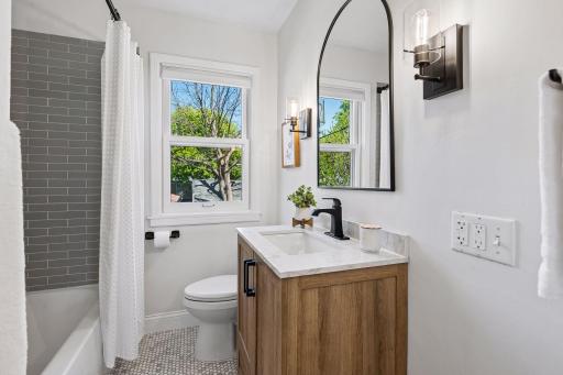 Completed updated main full bath with tile floors, tile surround in tub/shower, vanity, toilet, lighting and fixtures!! Modern yet timely for this home.