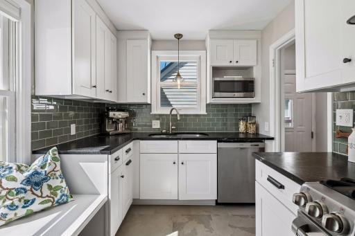 Luxurously updated kitchen offers beautiful tile backsplash, Soapstone countertops, custom cabinets, stainless steel appliances and even a little sitting nook to hang out with your chef!