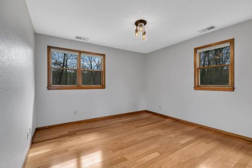 Primary bedroom on the main level offers engineered hardwood floors, natural light, and a large closet. Freshly painted ceiling & walls.