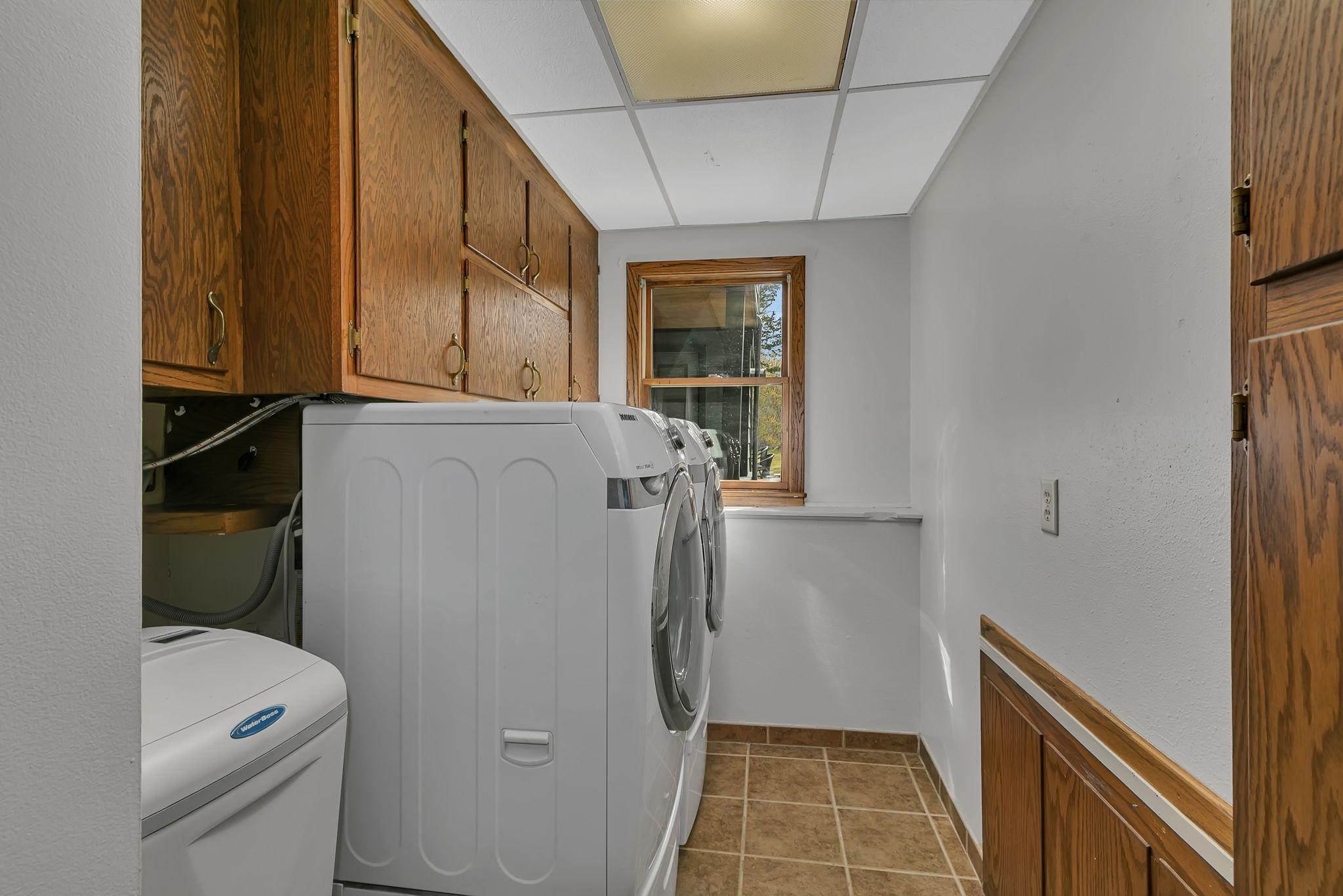 This laundry room offers a ton of cabinets for storage. It also includes the water heater & water softener.