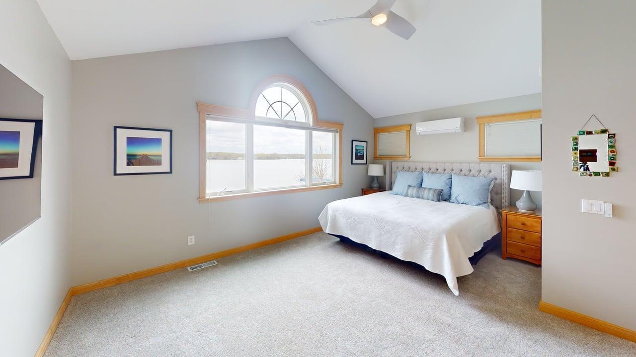 Primary bedroom on upper level w/vaulted ceiling and an incredible view of the lake