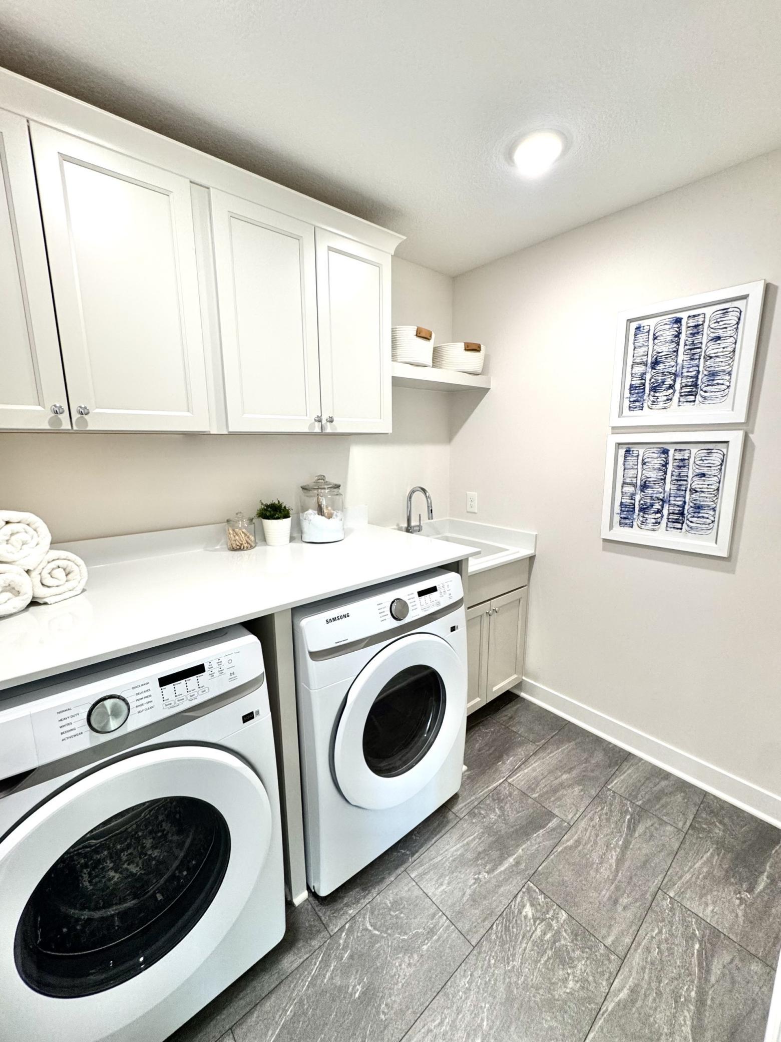 Laundry with cabinetry, deep sink, and quartz countertops