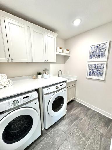 Laundry with cabinetry, deep sink, and quartz countertops