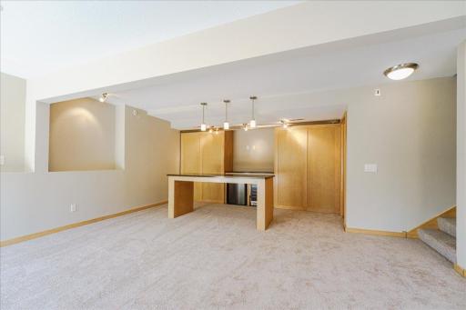 Bar area featuring large island w/ granite countertop and pendant lighting. Incudes wine fridge, beverage fridge, surround sound system and sliding doors for extra storage.