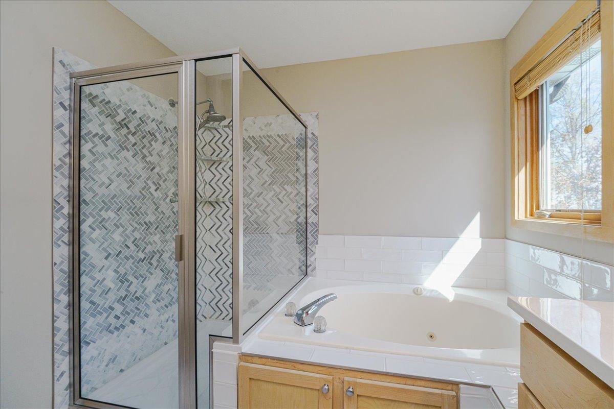 Walk-in shower w/ mosaic tile surround and glass door. Deep soaking jetted jacuzzi tub