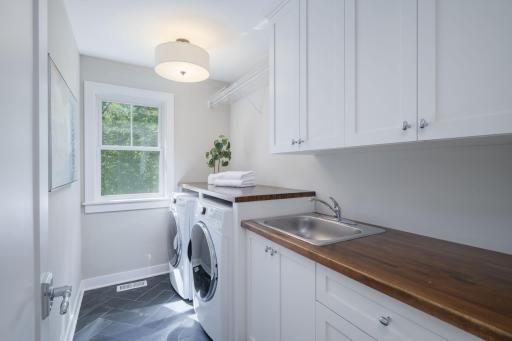 Upper-level laundry done right. A spacious room with a full-size washer and dryer and a utility sink, butcher block, folding counter, and abundant cabinetry make laundry day almost enjoyable.