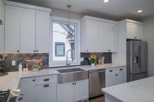The farmhouse sink, artisan backsplash tile, and garden window view bring warmth and character to a kitchen that was clearly designed with the home cook in mind.