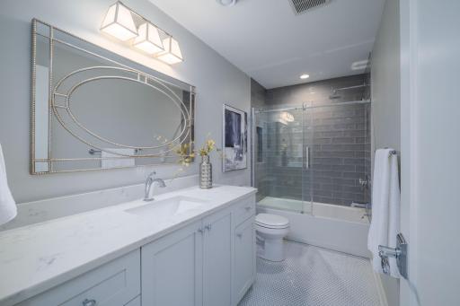 The Laura Level Bath is a standout. Floor-to-ceiling dark tile and an oversized round mirror in a long quartz vanity deliver a moody spa-inspired finish that feels fabulous.